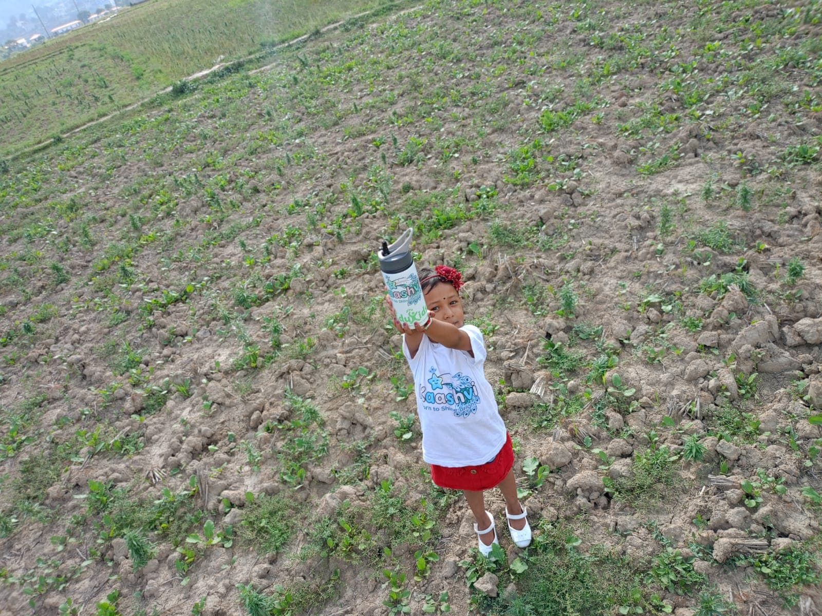 Kaashvi holding her personalized water bottle while wearing her matching name T-shirt from TOTOPASA